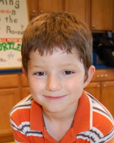 Young boy smiling in orange shirt