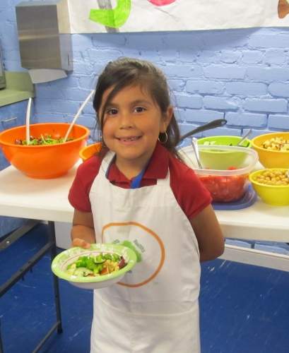 Child holding a salad smiling