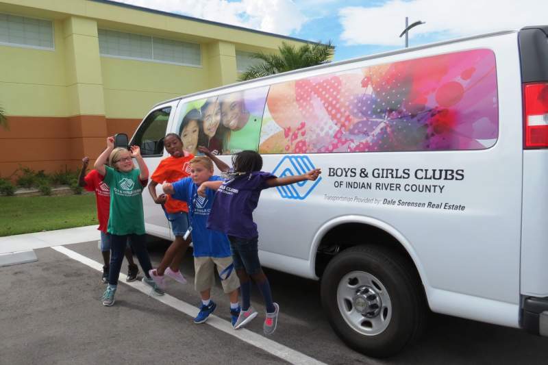 Children smiling and jumping in front of BGCIRC van